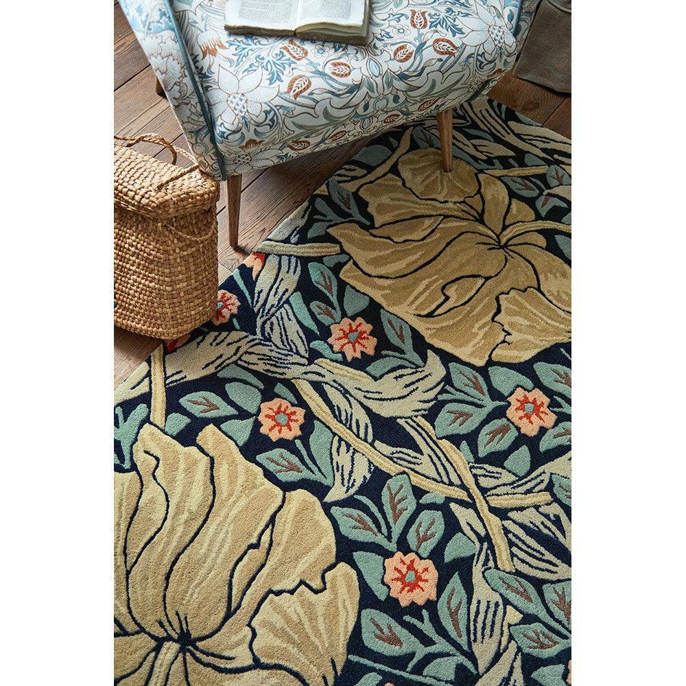 Morris & Co Pimpernel Indigo Rug featuring botanical floral pattern in navy, beige, teal and coral on dark background, hand-tufted wool
