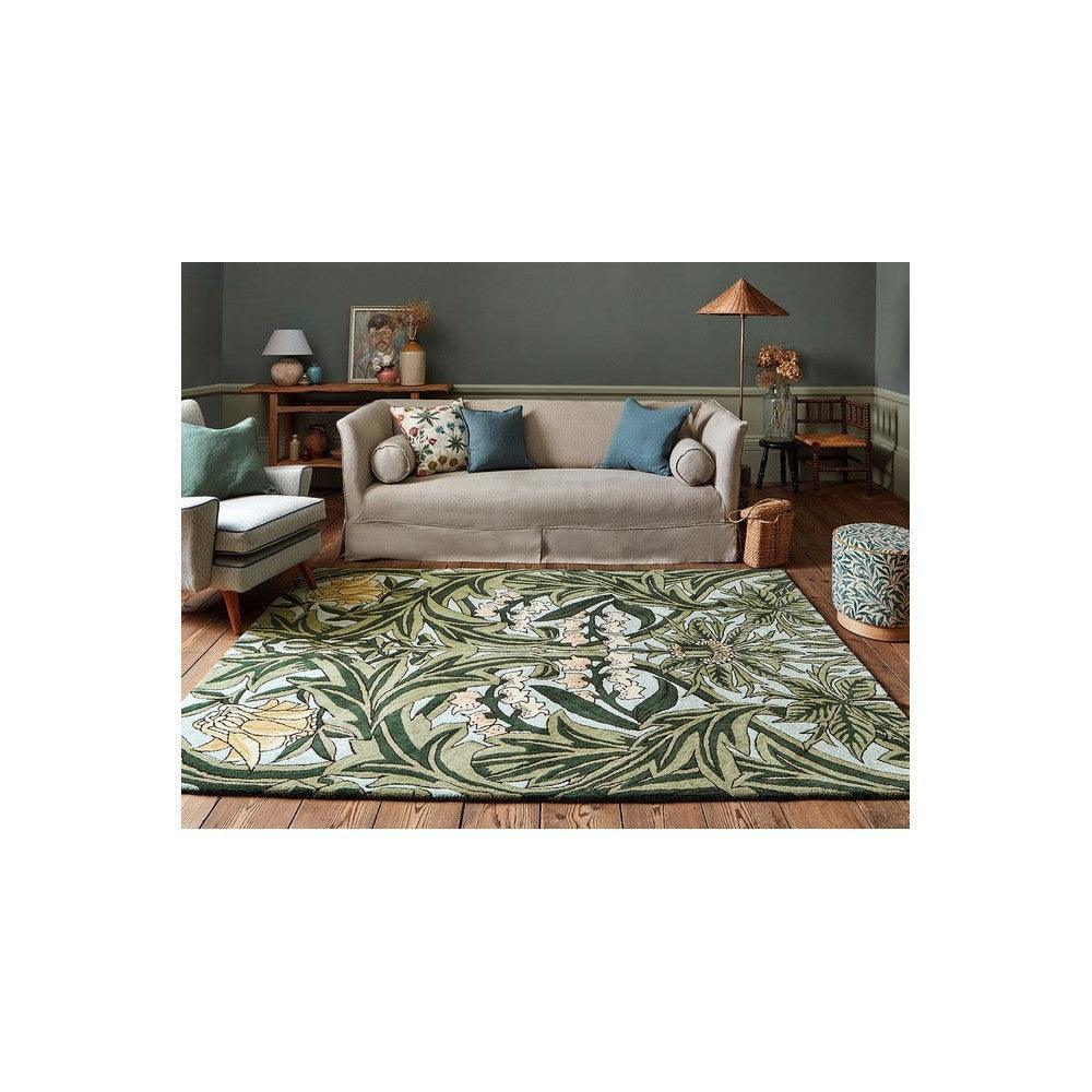 Morris & Co Bluebell Leafy Arbour Green Designer Rug featuring leafy botanical pattern in green, sage, cream and pale yellow on warm brown wood floor, hand-tufted wool