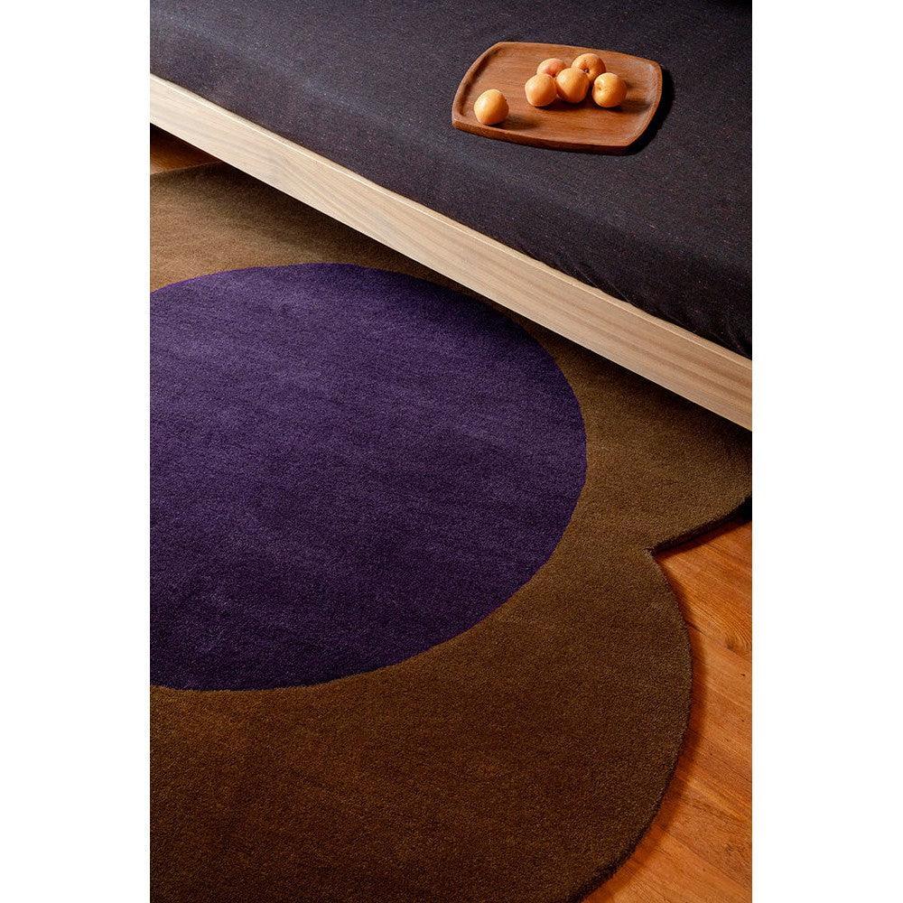 Orla Kiely Flower Spot rug featuring circular pattern in chestnut brown and deep violet on warm timber floor, hand-tufted wool