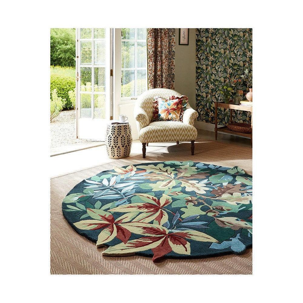 Sanderson Robin's Wood rug featuring tropical leaf pattern in forest green, teal, cream on beige background, hand-tufted wool