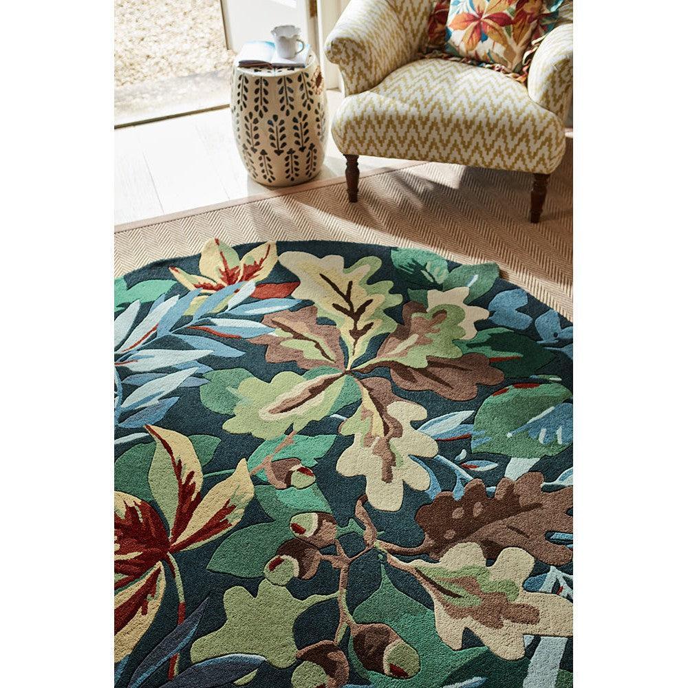 Sanderson Robin's Wood round designer rug featuring botanical leaf pattern in forest green, emerald, olive, cream on dark green background, hand-tufted wool