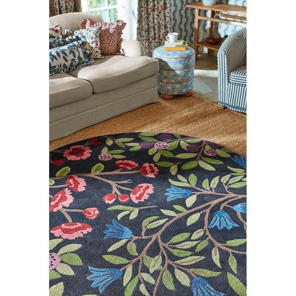 Sanderson Foraging Indigo Round Designer Rug featuring floral pattern in navy, pink, red, green and blue on indigo background, machine-made wool