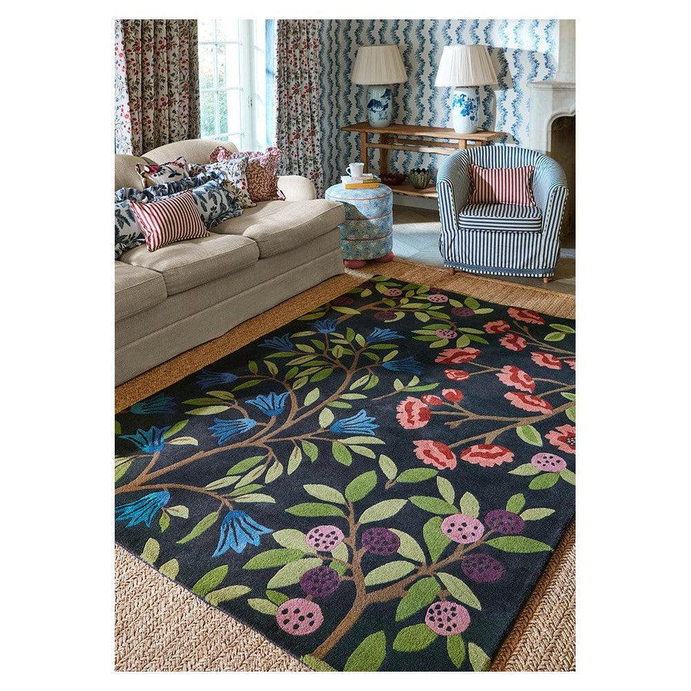 Sanderson Foraging Indigo Designer Rug featuring floral botanical pattern in indigo, greens, pinks on navy background, hand-tufted wool