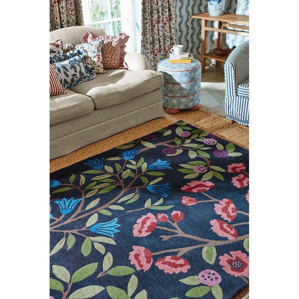 Sanderson Foraging Indigo Rug featuring botanical floral pattern in navy, emerald green, pink on indigo background, hand-tufted wool