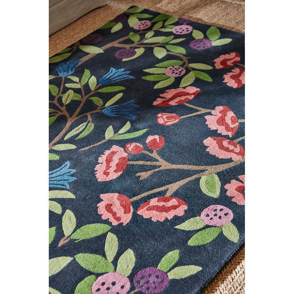Sanderson Foraging Indigo Designer Rug featuring botanical floral pattern in indigo, pink, green and blue on navy background, hand-tufted wool