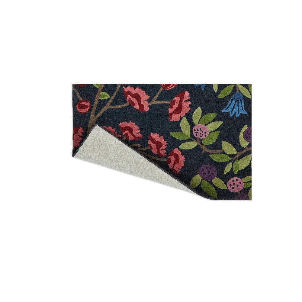 Sanderson Foraging Indigo Designer Rug featuring botanical floral pattern in navy, pink, red, lime green and purple on dark background, hand-tufted wool