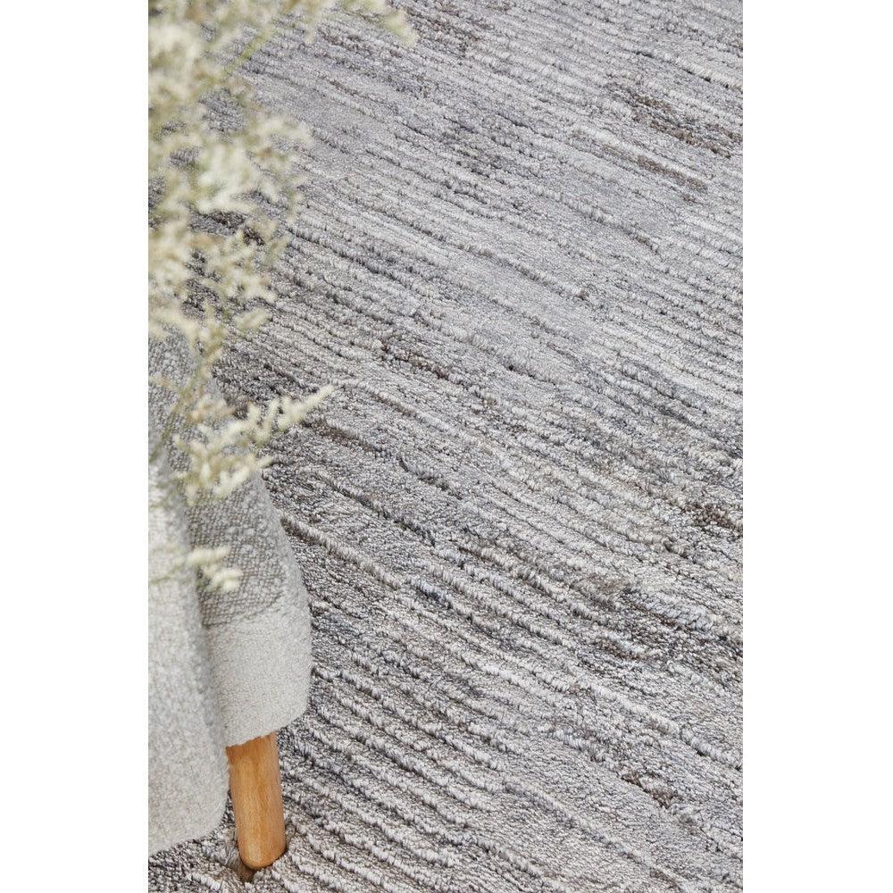 Himali Fin Steel Rug featuring textured striped pattern in steel grey, ivory and charcoal on light cream background, hand-tufted wool