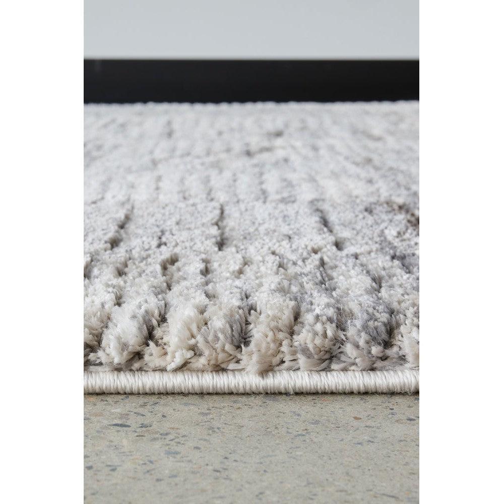 Himali Fin Steel Rug featuring shaggy pile in steel grey, ivory and beige on light concrete background, hand-tufted wool