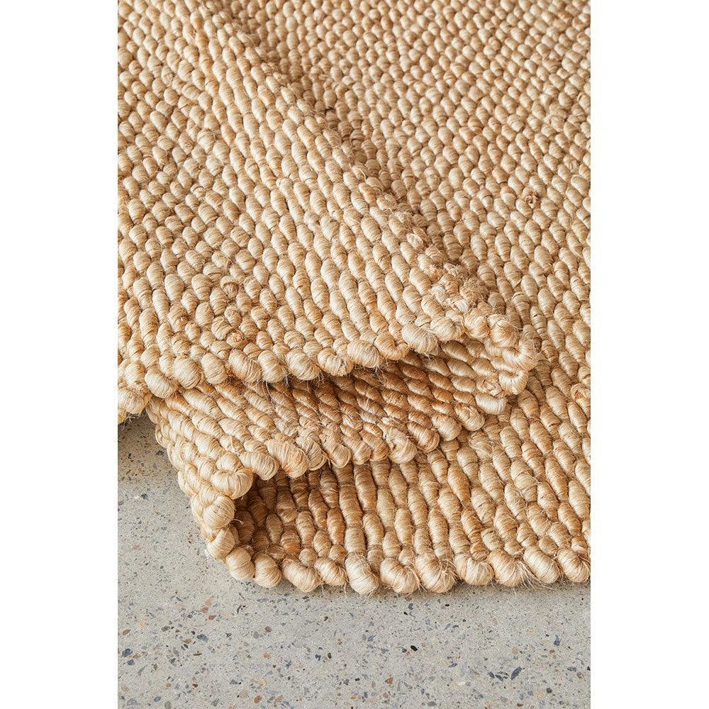Hive Natural Rug featuring chunky looped texture in natural beige and cream on grey floor, hand-woven jute
