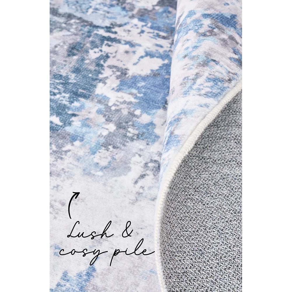 Revive Cato Blue Rug featuring abstract cloud-like pattern in blue, ivory and pale grey on light grey backing, hand-tufted wool
